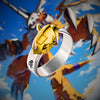 Bague dorée WarGreymon Digimon posée sur fond d’illustration