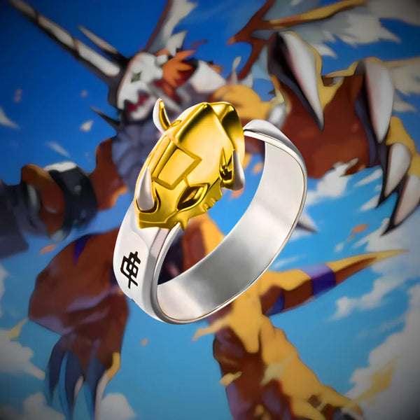 Bague dorée WarGreymon Digimon posée sur fond d’illustration
