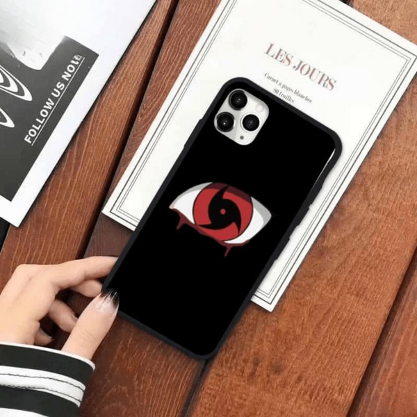 Coque noire pour iPhone avec le design du Mangekyō Sharingan d'Itachi Uchiwa de Naruto, tenue en main.