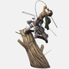 Vue de profil de la figurine de Mikasa Ackerman, montrant la dynamique de son mouvement et le détail de son équipement tridimensionnel sur le tronc d'arbre.