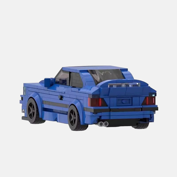 Vue de profil de la BMW M3 E36 en briques, montrant sa longueur et les détails du modèle.