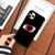 Coque noire pour iPhone avec le design du Mangekyō Sharingan d'Itachi Uchiwa de Naruto, tenue en main.