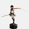 Figurine de Mikasa Ackerman de L'Attaque des Titans, en pose de soldat avec son uniforme du Bataillon d'exploration, son écharpe rouge et ses lames rengainées.