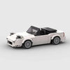 Vue de profil de la Mazda MX-5 NA en briques, montrant sa longueur et ses détails.